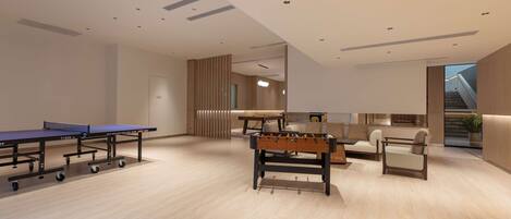 A modern indoor space with ping pong tables, a foosball table, and a sofa area.