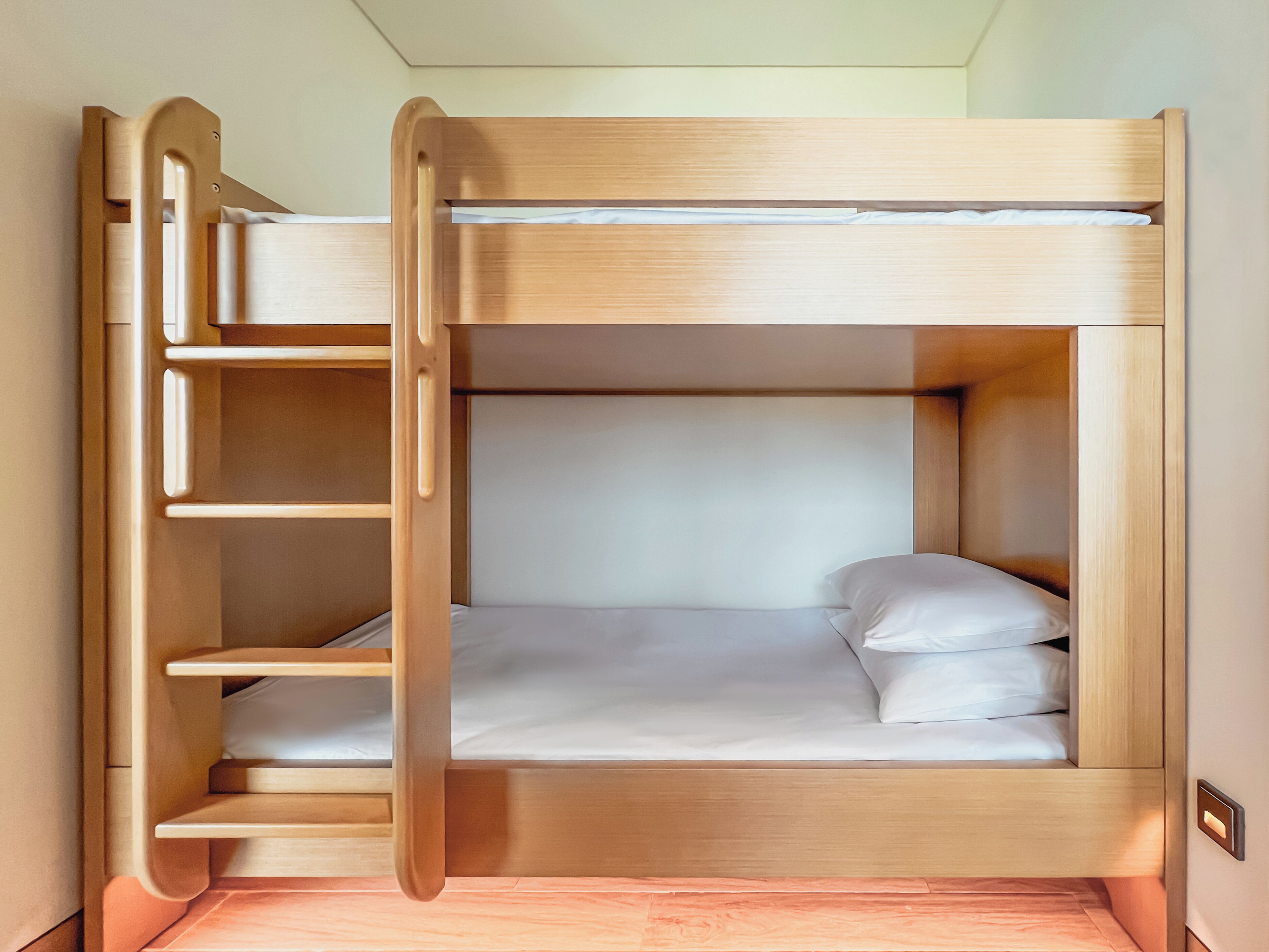 Una litera con estructura de madera, una escalera plegable y un estante.