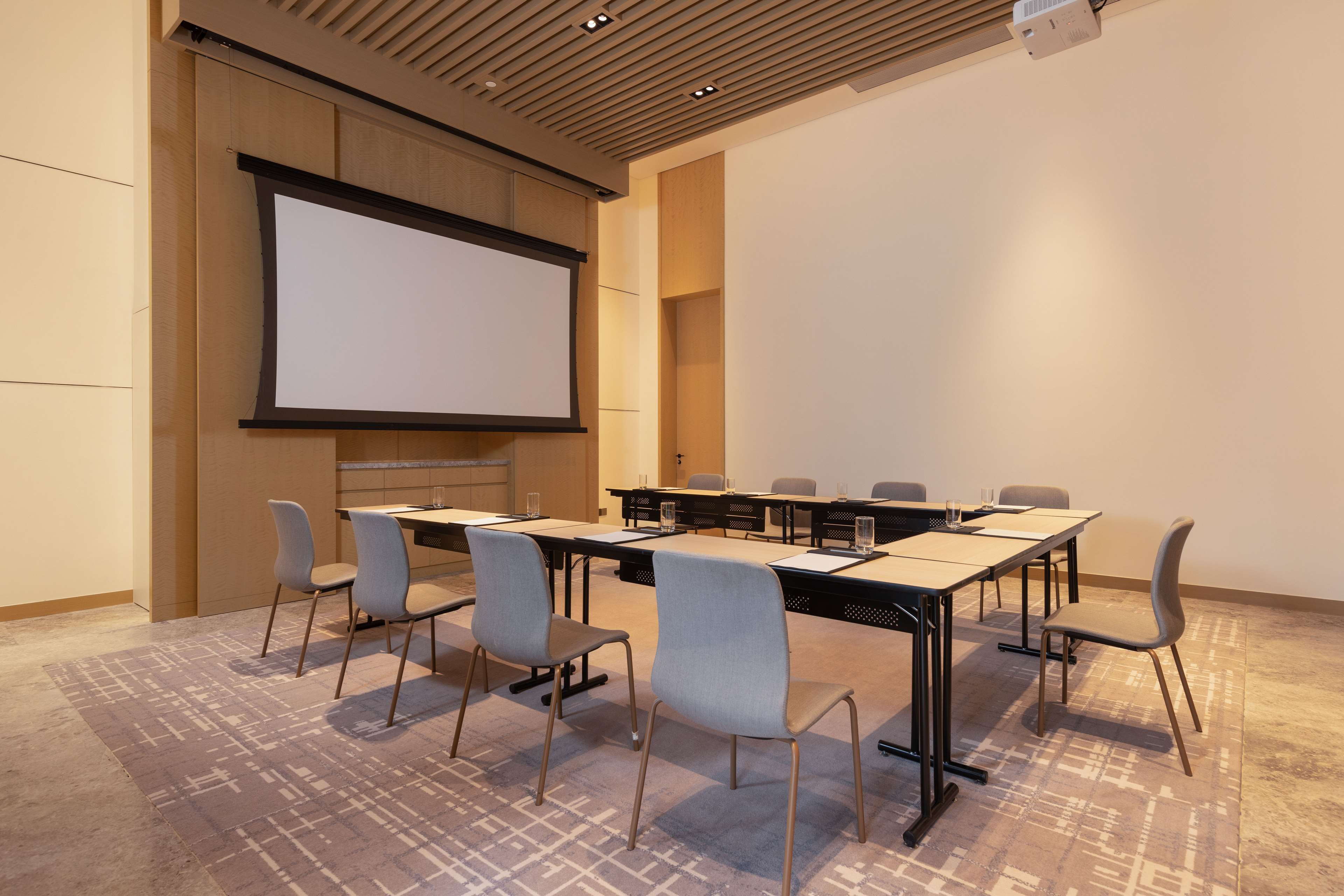 Une salle de conférence équipée d’un grand écran, d’une longue table et de six chaises.