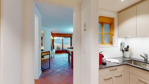 A modern kitchen with a window, a dining area with a view, and a hallway leading to a living space. - The newly renovated holiday apartment "Abitaziun Caspar Badrutt 306" in St. (St. Moritz)