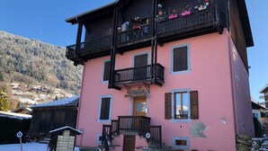 Un edificio rosa con un balcón, contraventanas de madera y un letrero que dice "RESIDENCE LES BRUYERES".
