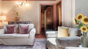 Ein gemütliches Wohnzimmer mit zwei weißen Sofas, einem gemusterten Teppich und einer Vase mit Sonnenblumen.