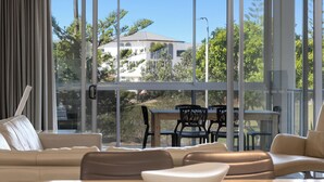 Un saló modern amb un finestra gran, una zona de menjador amb taula i cadires, i un sofà.
