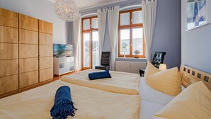 Habitación de hotel con dos camas, un armario de madera, un televisor y vistas a la ciudad a través de amplias ventanas.