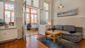 Amplia sala de estar con un sofá gris, una mesa de centro de madera y un ventanal grande.