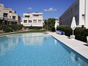 Une piscine à l’eau d’un bleu limpide, entourée d’une terrasse dallée.