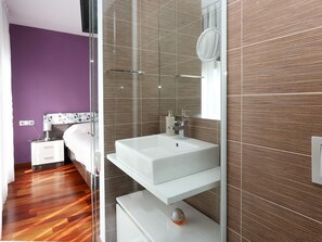 Une salle de bain moderne avec une douche à parois de verre, un lavabo blanc et un miroir.