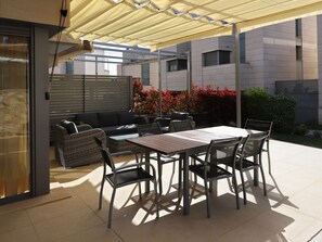 Une terrasse extérieure avec une table et des chaises, un canapé et une pergola offrant de l’ombre.