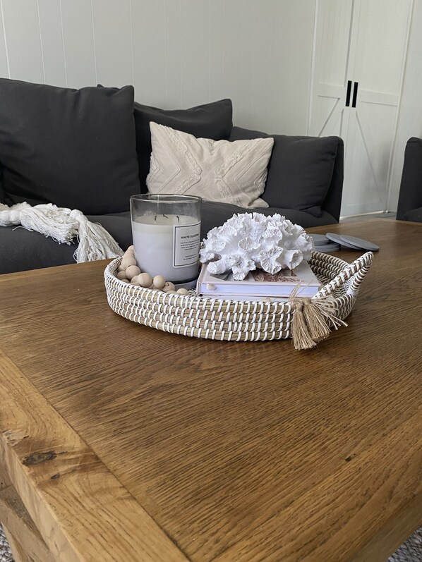 A wooden coffee table with a white candle, a woven basket, and decorative items. - Coastal family home central to everything! (Culburra Beach)