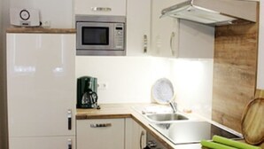 A compact kitchen with a microwave, oven, sink, and wooden countertop. - Vacation apartment Am Obstbaum "Apple" (Golßen OT Zützen)
