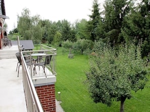 A balcony with outdoor furniture, a brick wall, and a green lawn with trees. - Vacation apartment Am Obstbaum "Apple" (Golßen OT Zützen)