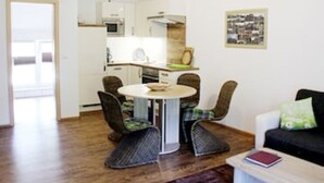 A compact living space with a dining area, kitchenette, and a sofa. - Vacation apartment Am Obstbaum "Apple" (Golßen OT Zützen)