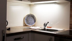 A kitchen with a microwave, stove, sink, and a round, textured object on the counter. - Ferienwohnung "birne" Am Obstbaum (Golßen OT Zützen)