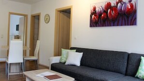 A modern living room with a grey sofa, a coffee table, and a painting of flowers on the wall. - Ferienwohnung "birne" Am Obstbaum (Golßen OT Zützen)