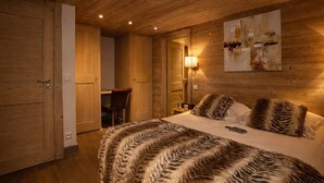 A wooden-paneled room with a bed, a desk, and a chair. - Luxurious Chalet in Courchevel-La Tania: Sleeps 12, Ski-in/Ski-out, Jacuzzi, Sauna & Home Cinema (La Tania)