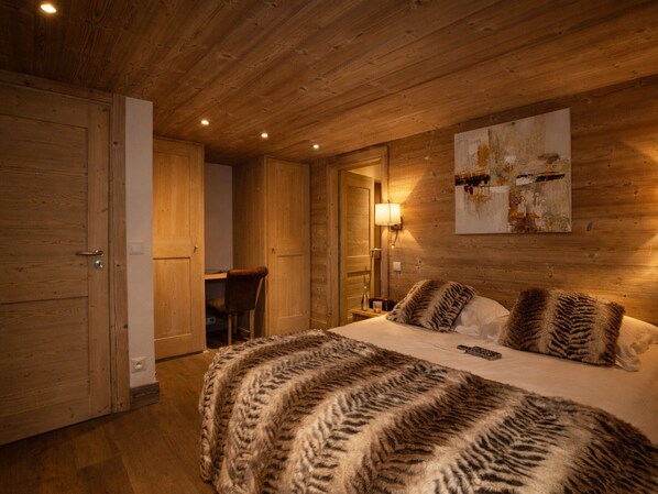 Quarto com painéis de madeira, uma cama, uma escrivaninha e uma cadeira.