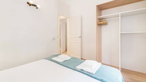 Une chambre à coucher avec un lit, une couvre-lit bleue et un mur blanc.