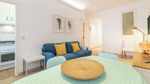 Un salon moderne avec un canapé, une table ronde en bois et un coin repas.