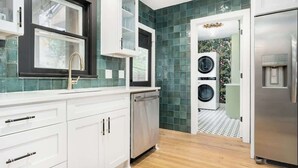 A modern kitchen with white cabinetry, a stainless steel dishwasher, a built-in washing machine, and a refrigerator.