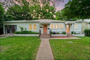 Une maison de plain-pied avec une entrée à l’avant, une boîte aux lettres bien visible et un jardin devant la maison.
