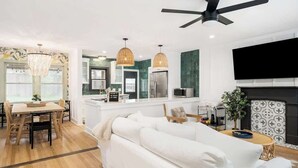 A modern living room with a white sofa, dining table, and chandelier.