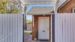 Una casa con puerta blanca, fachada de ladrillo y cerca de madera.