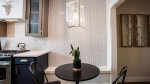 Una cocina moderna con un salpicadero de diseño herringbone, una mesa redonda negra con una planta en maceta y una lámpara colgante.