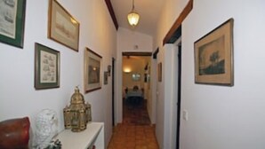 A narrow hallway with framed pictures on the walls, a small table with a decorative item, and a red chair. - Lovely rural house at Carcans close to lakes and surfing beaches (Carcans)