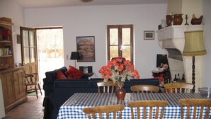 A dining area with a checkered tablecloth, wooden chairs, a vase with flowers, and a painting on the wall. - Lovely rural house at Carcans close to lakes and surfing beaches (Carcans)