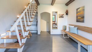A modern interior with a wooden staircase, a bench, and a painting on the wall. - The vacation home Dat Reethuus in St. Peter-Ording for up to 5 people (St Peter-Ording)