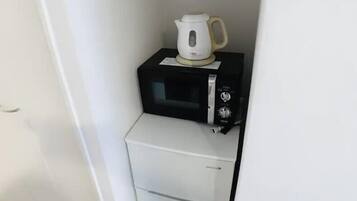 A compact kitchenette with a microwave and a small refrigerator.