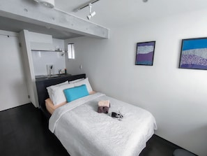Une chambre moderne avec un lit, un bureau intégré et des œuvres d’art accrochées aux murs.