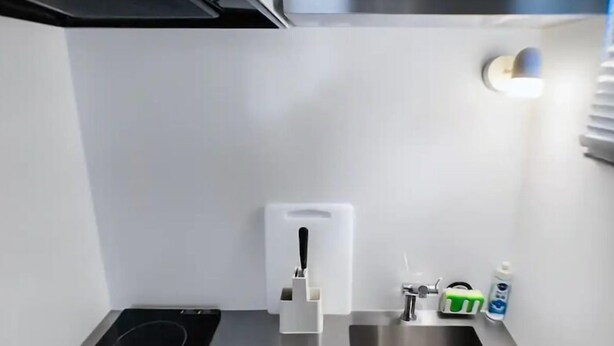 Cocina compacta con estufa integrada, pileta de acero inoxidable y una pequeña mesada.