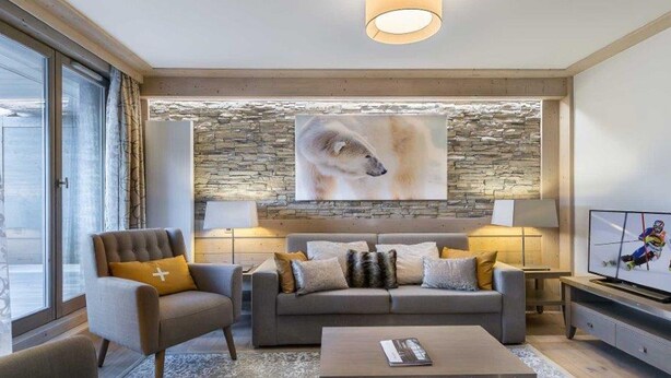 A modern living room with a stone accent wall, a large painting of a dog, and a television. - Modern apartment in Courchevel with parking and WiFi (Courchevel 1550)