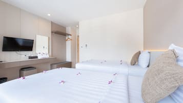 Een hotelkamer met twee bedden, een televisie, een spiegel en een klein bureau.