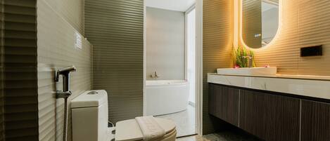 Une salle de bain moderne équipée d’un WC, d’un bidet, d’une baignoire et d’un meuble-lavabo avec un miroir.