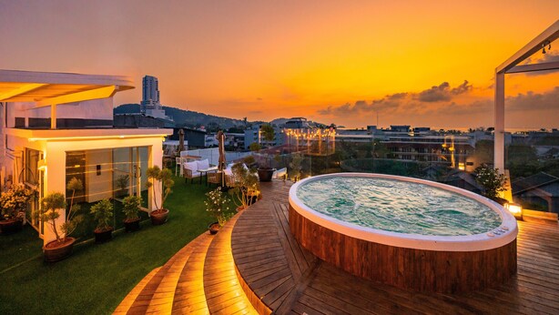 Una terraza en la azotea con jacuzzi, cubierta de madera y plantas en macetas.