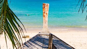 Un muelle de madera que lleva a una playa con agua turquesa cristalina y islas distantes.