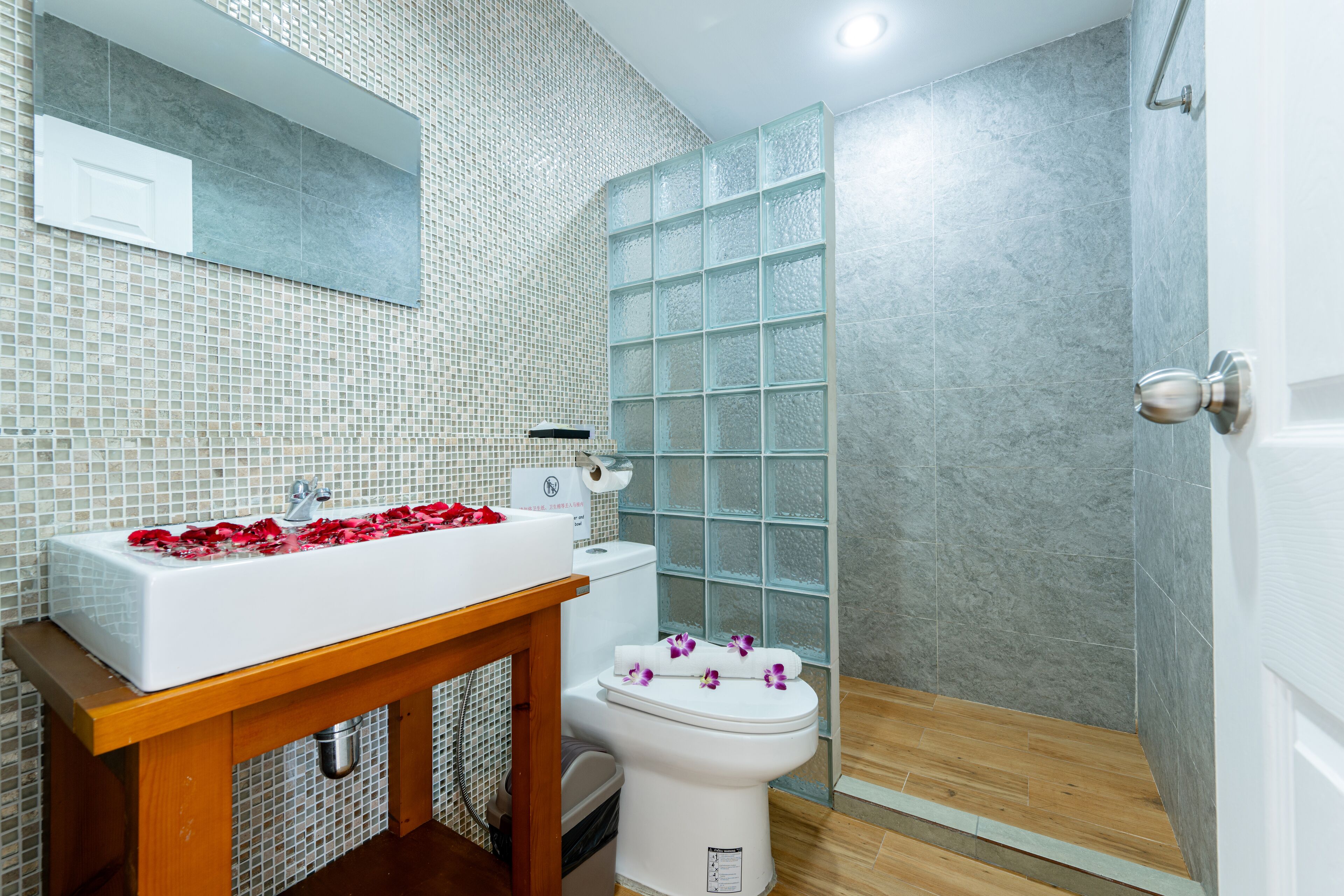 A bathroom with a white sink, toilet, and shower area.