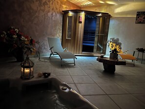 Un espace bien-être comprenant un jacuzzi, des chaises longues et une salle de massage.