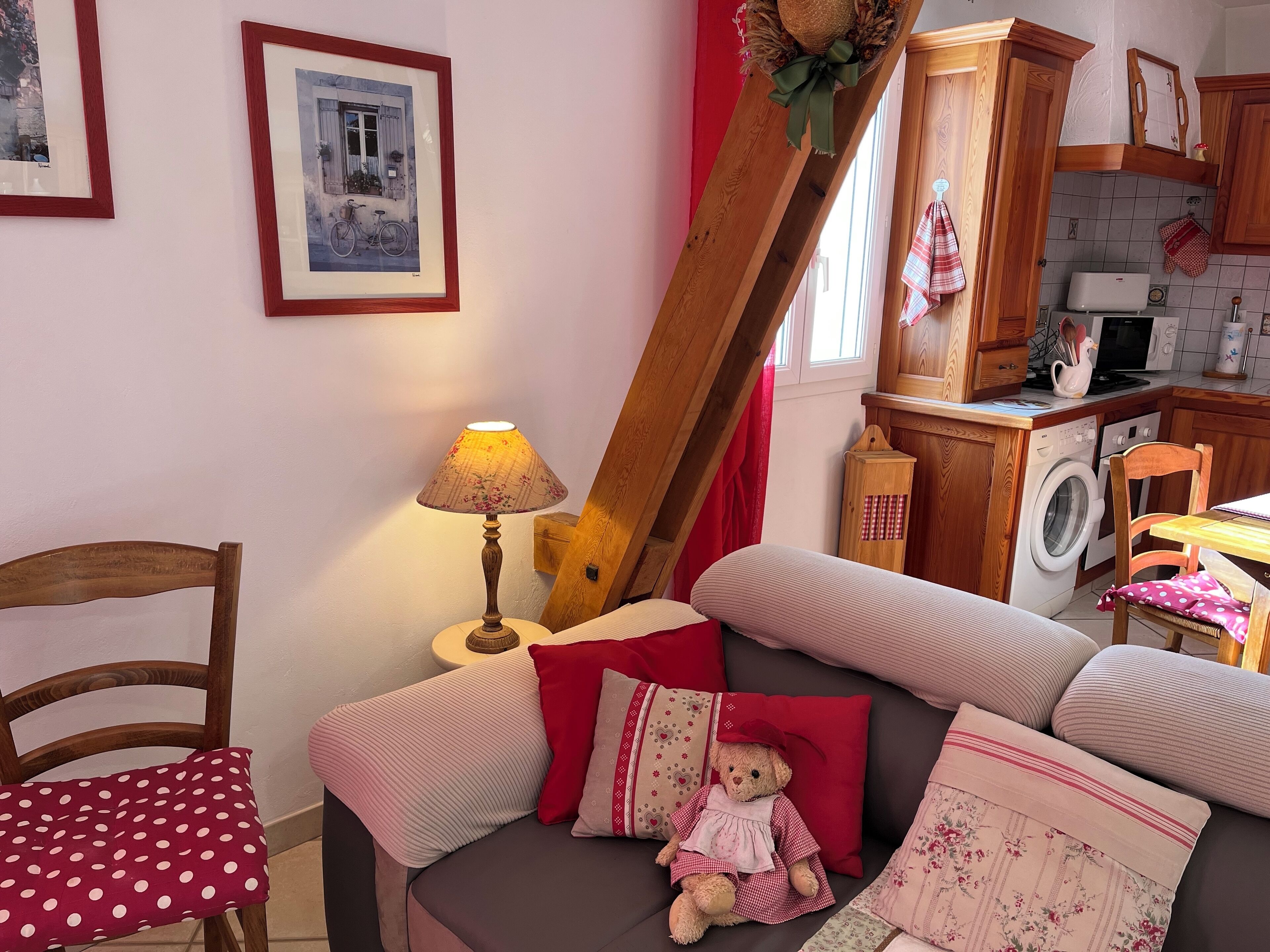 A cozy living room with a sofa, a chair, a lamp, and a teddy bear.