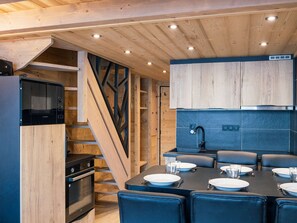 Uma cozinha moderna com armários de madeira, forno embutido e um espaço de refeições com mesa posta para quatro pessoas.