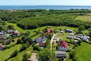 Una vista aerea di una zona residenziale con case, prati verdi e un corpo d'acqua sullo sfondo.