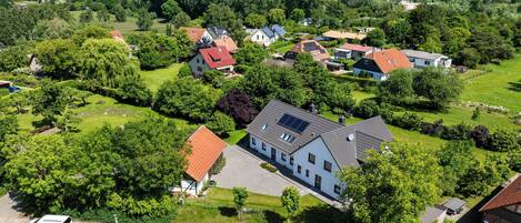 Une vue aérienne d’un quartier résidentiel avec des maisons, des pelouses verdoyantes et un ciel bleu dégagé.