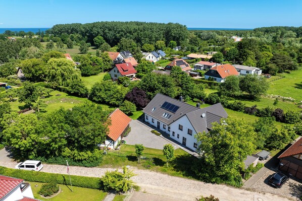 Une vue aérienne d’un quartier résidentiel avec des maisons, des pelouses verdoyantes et un ciel bleu dégagé.