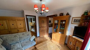 Un soggiorno con un divano, armadietti in legno, una televisione e un lampadario.