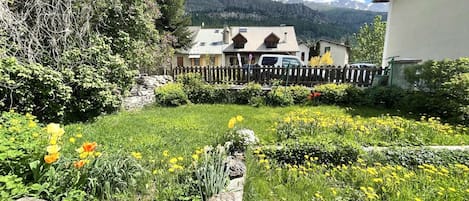 A garden with a stone wall, yellow flowers, and a wooden fence.