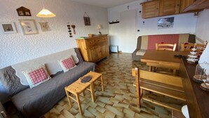 Tunnelmallinen olohuone, jossa on sohva, puinen pöytä ja kalanruotokuviolla oleva lattia.