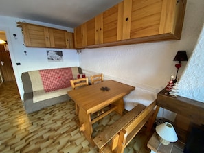 Una habitación acogedora con muebles de madera, un banco, una mesa y una chimenea.