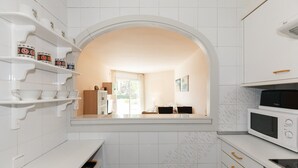 A modern kitchen with white cabinetry, a built-in microwave, and a window overlooking a dining area. - Ground floor first sealine 009 UHC Los Flamencos (Miami Playa)